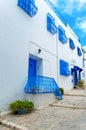 A narrow street in Mediterranean architectural style with blue and white windows and doors. Royalty Free Stock Photo