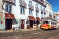 Narrow street with moving tramway on tram rails, past rustic houses in sunny capital city