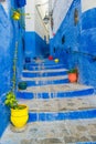 A narrow street in the old medina of Chefchaouen in Morocco, painted blue, with colourful planters. Royalty Free Stock Photo