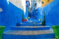 A narrow street in the old medina of Chefchaouen in Morocco, painted blue, with colourful planters. Royalty Free Stock Photo