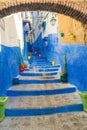 A narrow street in the old medina of Chefchaouen in Morocco, painted blue, with colourful planters. Royalty Free Stock Photo