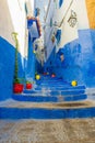 A narrow street in the old medina of Chefchaouen in Morocco, painted blue, with colourful planters. Royalty Free Stock Photo