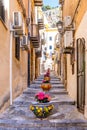 Narrow street in the old town of Cefalu, medieval village on Sicily island, Italy. Flower pots with traditional sicilian Royalty Free Stock Photo