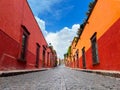 Narrow street between traditional buildings under blue cloudy sky in San Miguel de Allende, Mexico Royalty Free Stock Photo