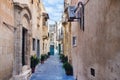 Narrow street in Rabat, Malta with residential buildings at noon.