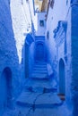 Narrow street with steps and some houses with old doors, all painted blue in the medina of Chefchaouen, Morocco Royalty Free Stock Photo