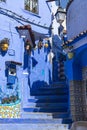 Narrow street with steps and some houses with old doors, all painted blue in the medina of Chefchaouen, Morocco Royalty Free Stock Photo