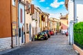 Narrow street of the village of fishermen San Giuliano with colorful houses, cars and a bicycles during sunny summer day in Rimini
