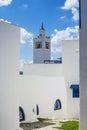 Narrow streets of the city in the Andalusian style in white-blue colors, and minaret mosque in the background