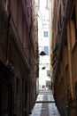 The narrow streets of the city of Genoa Italy. Old cobblestone road in the window grilles. Beautiful Perspective Lane. A good Royalty Free Stock Photo