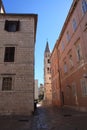 Narrow streets of a European city with red roofs and stone walls. A platform of stone and a shadow in the city. A chapel in the