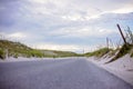 Narrow strip of blacktop road between sandy beach dunes in Pensacola