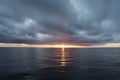 Narrow strip of sunset over the calm sea and very dark dense clouds