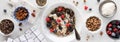 A narrow view of an oat yoghurt bowl with all the fixings surrounding.