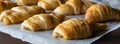 Narrow view of a parchment lined baking sheet topped with rows of freshly baked crescent rolls topped with caramel sauce
