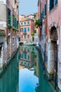 Narrow water canal and red brick worn out buidings built on water in Venice, Italy