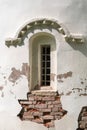 A narrow window with iron bars in the wall of an old church.