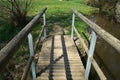 Narrow wooden bridge over a river in a park Royalty Free Stock Photo