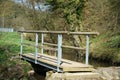 Narrow wooden bridge over a river in a park Royalty Free Stock Photo