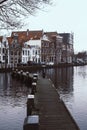 Narrow wooden bridge over the water of river Spaarne in Haarlem, Netherlands. Traditional dutch houses on a background