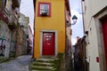 Narrow yellow house with cute red windows and entrance door surrounded by narrow lanes in old town of Porto, Portugal. Royalty Free Stock Photo