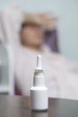 Nasal Spray. The bottle is on the table. Against the background of a woman who touches her forehead with her hand. Royalty Free Stock Photo