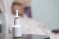 Nasal Spray. The bottle is on the table. Against the background of a woman who touches her forehead with her hand. Royalty Free Stock Photo