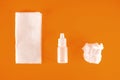 Nasal spray and used paper handkerchiefs on an orange background with a copy of the space. The concept of treating a cold or