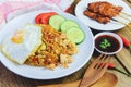 Nasi goreng fried rice chicken with egg tomato cucumber on white plate and satay with sauce - Nasi Goreng Ayam indonesian food Royalty Free Stock Photo