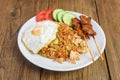 Nasi goreng fried rice chicken with egg tomato cucumber on white plate and satay with sauce - Nasi Goreng Ayam indonesian food