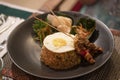 Nasi goreng, a traditional balinese food served during the dinner in a black plate with vegetables and side dish in a restaurant