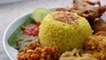Nasi Kuning or Yellow rice with traditional fried chicken, tofu, tempeh, and smashed potato. Royalty Free Stock Photo