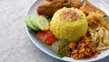 Nasi Kuning or Yellow rice with traditional fried chicken, tofu, tempeh, and smashed potato. Royalty Free Stock Photo