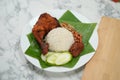 Close-up Nasi Lemak dish with chicken drum stick on marble surface with coconut leaf