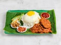 nasi lemak set with sunny egg, rice, chicken chop, pickle, salad, peanut and chilli sauce served in dish isolated on banana leaf Royalty Free Stock Photo