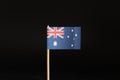 A national Flag of Australia on wooden stick on black background. State belongs on australia continent.