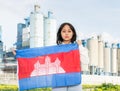 National flag of Cambodia in hands of girl against background of modern factory