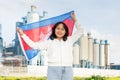 National flag of Cambodia in hands of girl against background of modern factory