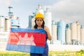 National flag of Cambodia in the hands of girl in overalls against background of modern metallurgical plant