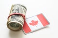 The national flag of Canada sticking in a pile of american dollars.(series) Royalty Free Stock Photo