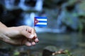 National Flag Of Cuba On Wooden Stick. Young Boy Holds National Athem Near Waterfall On Stream In Autumn Times. Concept Of