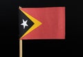 A national flag of East Timor on toothpick on black background. A red field with the black isosceles triangle based on the hoist-