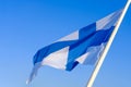 National flag of Finland waving on the wind against clear blue sky. Finnish flag on flagpole Royalty Free Stock Photo