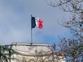 National flag of France on a flagpole in front of blue sky in Paris