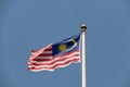 National flag of Malaysia on bright blue sky background. Blown away by wind. Royalty Free Stock Photo