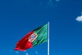 National flag of Portugal on a flagpole in front of blue sky. Royalty Free Stock Photo