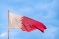 National flag of Qatar is flying in the wind against the blue sky