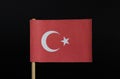 The national flag of the Republic of Turkey on toothpick on black background. A red field with a white star and crescent slightly