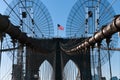 The national flag of United States of America winding on top of Brooklyn Bridge landmark from Manhattan.