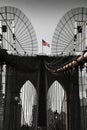 The national flag of United States of America winding on top of Brooklyn Bridge landmark from Manhattan.